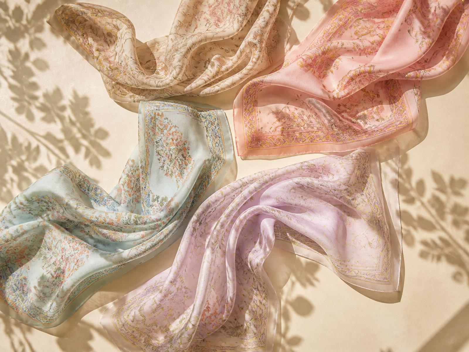 Pastel silk scarves flowing across cream surface